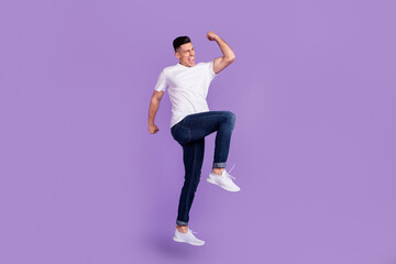 Fototapeta na wymiar Full size photo of young cheerful crazy man jump up raise fist winner enjoy isolated on violet color background