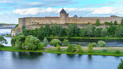 Medieval castle by the river with a great defensive wall and stone towers.