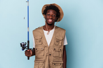 Young african american fisherman holding a rod isolated on blue background happy, smiling and cheerful.