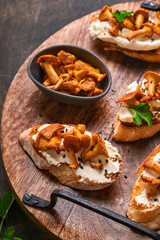 Chanterelle sandwiches with cheese. Open faced sandwich with creamy cheese, seasonings and pepper and fresh parsley on an old wooden background. Mock up. Top view.