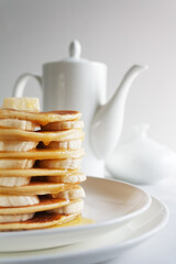 Stack of tasty pancakes with banana, nuts and syrup