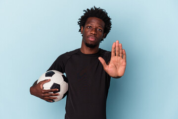 Young african american man playing soccer isolated on blue background standing with outstretched...