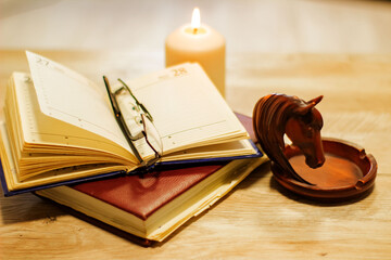 sketchpad glasses candles and horse head decoration on a wooden background