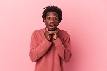 Young african american man isolated on pink background praying for luck, amazed and opening mouth looking to front.