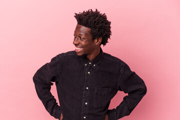 Young african american man isolated on pink background laughs happily and has fun keeping hands on stomach.