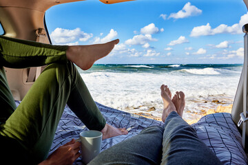 A young couple is resting in the car by the ocean.