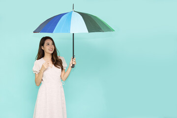 Young Asian woman holding umbella standing isolated on green background