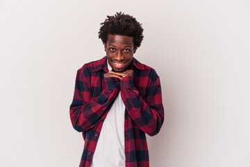 Young african american man isolated on white background  keeps hands under chin, is looking happily aside.