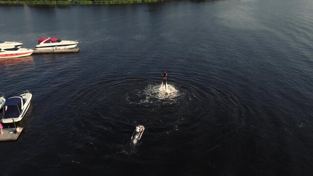 young guy is riding a flyboard near the pier. training. sunset. Drone view.