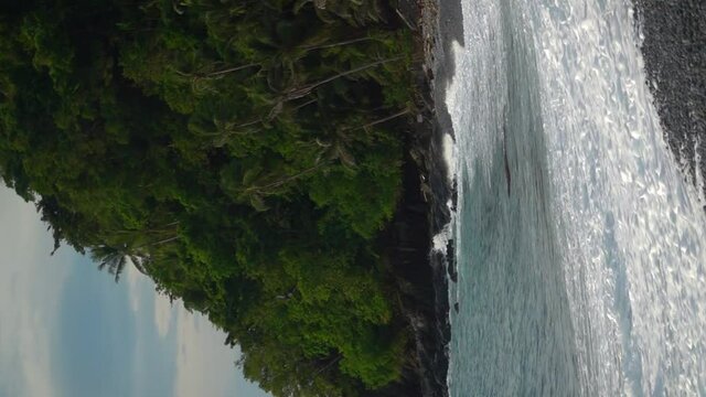 Vertical Video. Tropical island beach with waves crashing in slow motion onto the shore. Filmed in Looc beach, Surigao Philippines