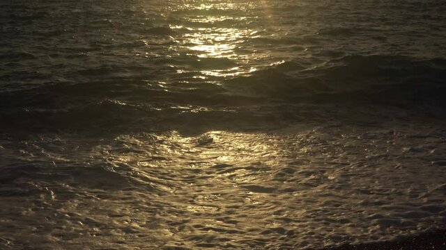Waves breaking onto a pebble beach at sunset. Filmed in real-time at Looc Beach in Surigao Philippines