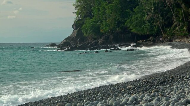 Tropical deserted island. Waves breaking on the shores of a pebble beach. Filmed in Looc Surigao Philippines