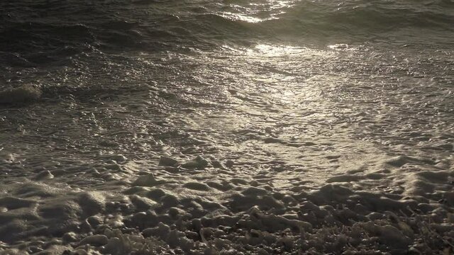 Waves crashing onto a pebble beach at sunset. A tropical scene filmed on location in Looc Beach Surigao Philippines.
