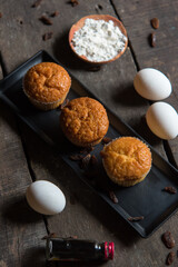 Confectionery item cupcakes in a black tray on a wooden background. Close up, selective focus. 