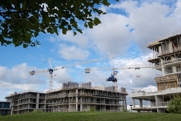 Fototapeta na wymiar Construction site with cranes and green grass in the foreground