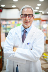 Fototapeta premium Senior pharmacist smiling and folding arms in his store