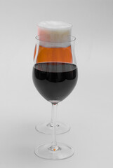 Glass of red wine and a glass of lager on white background.