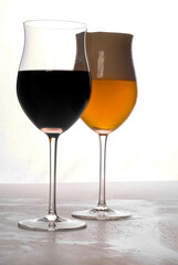 Glass of red wine and a glass of lager on white background.