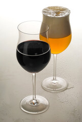 Glass of red wine and a glass of lager on white background.