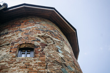 The wall of an old building made of red brick and stone. Window in the tower of an ancient castle