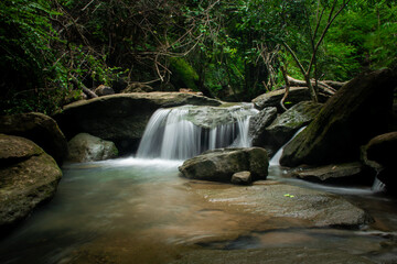 Waterfall in the midst of natural forest. The stream flowing through the rock channel.