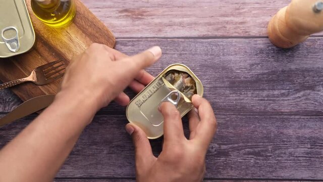 opening a tin of sardines on table 