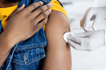 cropped view of doctor in latex gloves vaccinating african american man in clinic