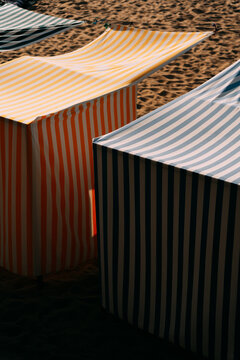 Gazebos with canopies on sandy beach in sunlight