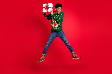 Full length body size view of attractive trendy cheery guy jumping holding giftbox Eve Noel custom isolated over bright red color background