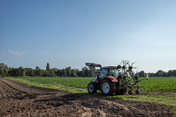 Obraz premium Working tractor cultivate and plough the soil on agricultural farm in countryside area in Europe.