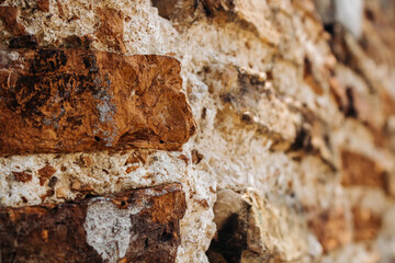 The wall of an old building made of red brick and stone. Brick wall close-up