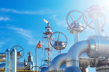 Gate valves on the background of a blue sky and an industrial torch.