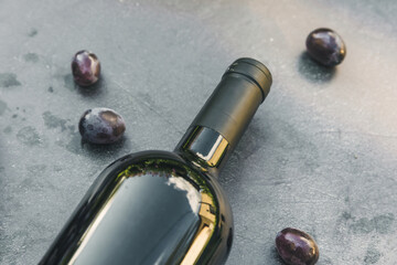 Bottle of red wine and ripe grape on vintage dark stone table background. Top view copy space for...