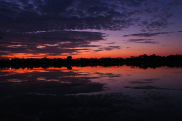 Beautiful symmetry of a dramatic sky in the water of a lake at sunset or sunrise. Stratus,...
