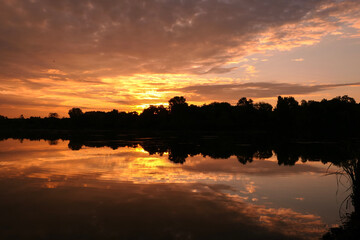 Beautiful symmetry of a dramatic sky in the water of a lake at sunset or sunrise. Stratus,...
