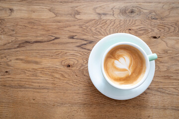 Outdoor Vintage mood, Cappuccino on top with heart flower latte art lay on wood texture table. Love latte art on coffee cappuccino . Heart and flower latte art pattern.