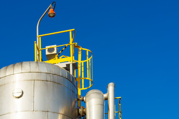The upper part of the vertical gas storage tank on the background of the blue sky.