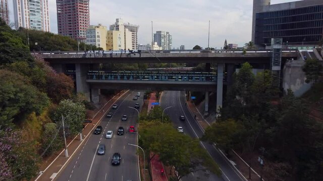 Dolly in aerial towards Sumare Bridge as a man does a Pendulum bungee jump. Sao Paulo Brazil.