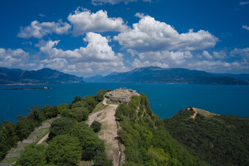 Fototapeta na wymiar Fortress with a cross on a hill in the background Lake Garda. Fortress Rocca di Manerba aerial view. Panorama on the rocca di manerba top view. Lake Garda, Italy aerial view.