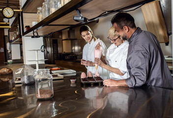 Group of bakers decorating desserts in modern manufacturing.