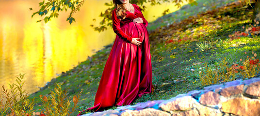 Banner with a pregnant woman. Maternity concept. The background is a lake in autumn, beauty and naturalness. Copy space