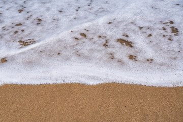 Ocean Nature image of close-up details as foamy water as waves wash up on shore at the beach 