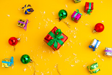 Gift box with a Christmas present on a yellow background, among the New Year's decorations