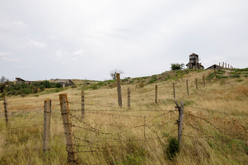 Abandoned buildings fenced with rusty barbed wire. The old observation tower.