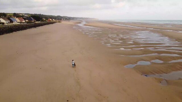 Young girl with a weimaraner dog playing on Omaha beach located in Normandy, France