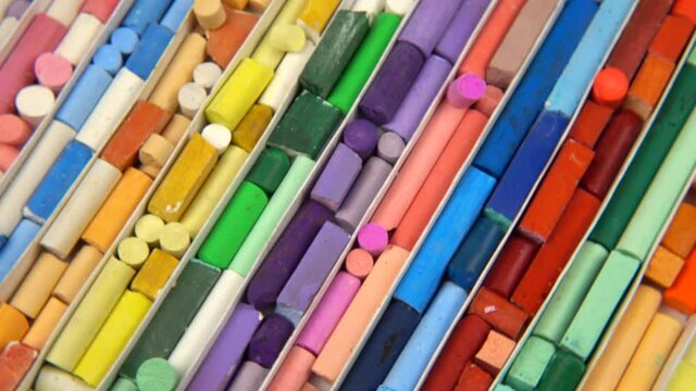 Multi-colored crayons of the various types, shapes and sizes lay out in separate cells in a box for storing crayons. Turntable, background