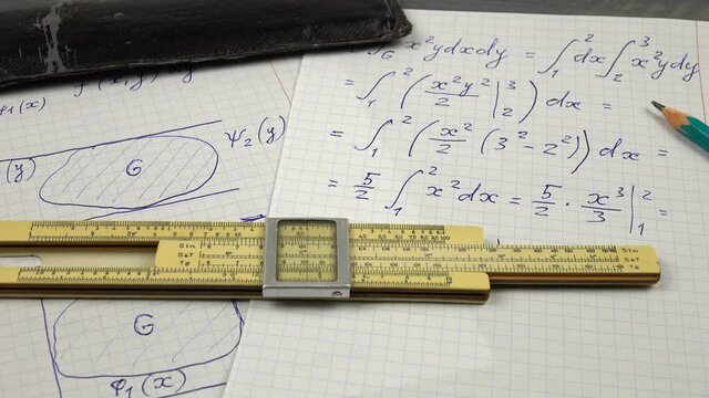 Vintage slide rule for performing of the mathematical computations, leather slide rule case and pencil lie on the pieces of paper with mathematical calculations 