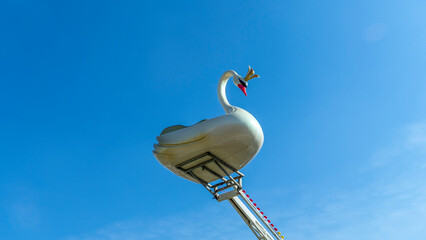 Part of the carousel in the form of swan against the classic blue sky. Lens flare. Space for text.