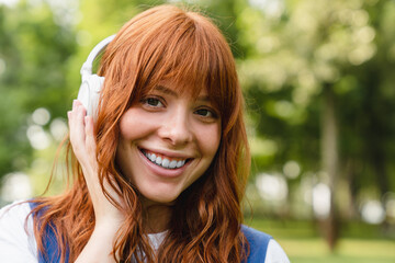 Smiling caucasian young woman girl teenager student listening to the mp3 stereo favorite song...