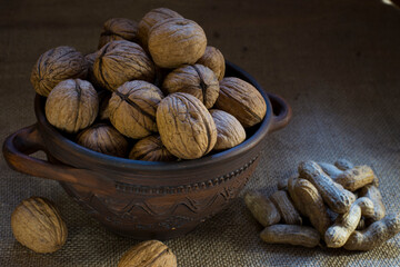 walnuts in a bowl. a plate with nuts. clay dishes. dessert, diet, vegetarianism. useful food, many vitamins. close-up. nuts in a dish against the background of burlap